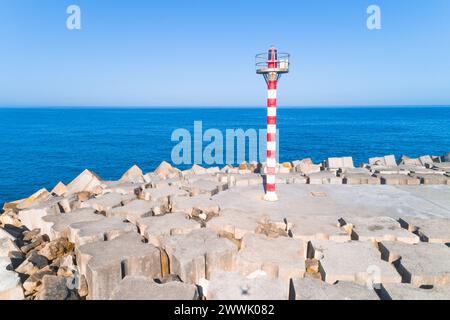 Blick auf einen kleinen Leuchtturm am Pier vor ruhigem Meer Stockfoto