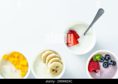 Auswahl an verschiedenen Joghurts mit Beeren, Früchten, Mango und Banane auf weiß. Gesundes Frühstück Stockfoto