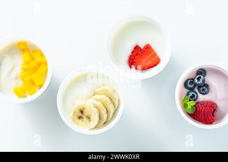 Auswahl an verschiedenen Joghurts mit Beeren, Früchten, Mango und Banane auf weiß. Gesundes Frühstück Stockfoto