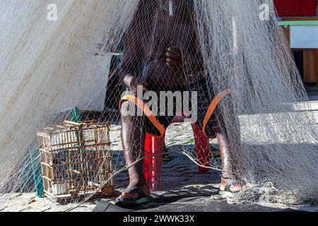 Santo Amaro, Bahia, Brasilien - 1. Juni 2019: Ein Fischer sitzt und repariert ein Fischernetz in Acupe, Santo Amaro, Bahia. Stockfoto