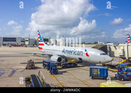 American Airlines Flugzeuge auf dem Asphalt während der Gepäckladung vor einem blauen Himmel mit weißen Wolken. Miami. USA. Stockfoto