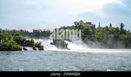 Beschreibung: Touristen beobachten die beeindruckenden Wasserfälle unter Schloss Laufen am Rheinfall von den Felsen und Touristenbooten aus. Rheinfall, Neuhausen Stockfoto