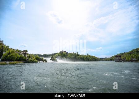 Beschreibung: Panoramablick auf Touristen, die die beeindruckenden Wasserfälle unter Schloss Laufen am Rheinfall von den Felsen und Touristenbooten aus erleben Stockfoto