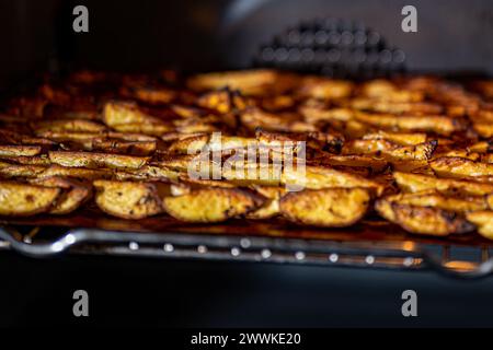 Beschreibung: Knusprige, goldbraune, gebackene Kartoffelkeile mit Paprika, Knoblauch, Salz, Pfeffer, Rosmarin, basilikum auf dem Tablett im Ofen, fotografiert von Stockfoto