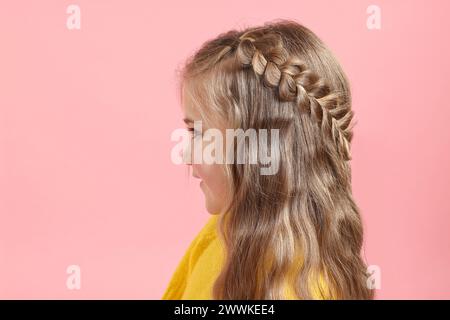 Süßes kleines Mädchen mit geflochtenen Haaren auf rosa Hintergrund Stockfoto