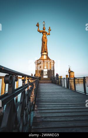 Beschreibung: Die Touristen genießen die sonnige abendliche Atmosphäre am Bootssteg mit der Wahrzeichen-Statue von Imperia. Hafen, Konstanz, Bodensee, Ba Stockfoto