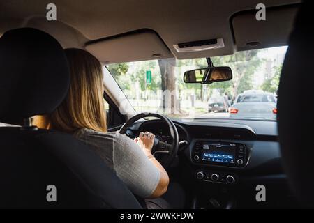 Frau, die ein modernes Auto durch die Stadt fährt und das Hupe hupt. Innenansicht. Stockfoto