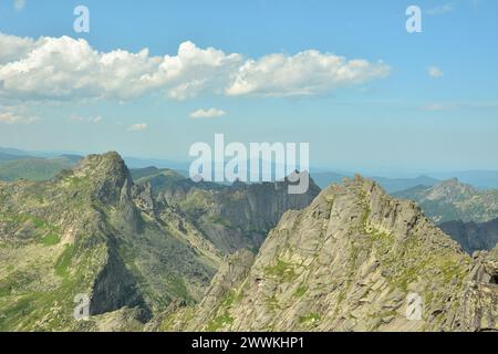 Spitze Gipfel hoher, steiler Klippen unter einem klaren, wolkigen Himmel im Sommer. Naturpark Ergaki, Gebiet Krasnojarsk, Sibirien, Russland. Stockfoto