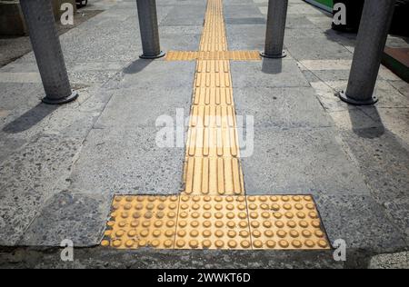 Gelber taktiler Pflaster für Blinde oder Sehbehinderte auf dem Gehweg. Stockfoto