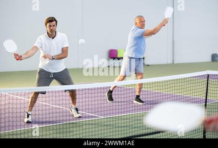 Erwachsener Mann, der Doppel-Pickleball im Team mit älterem Partner spielt Stockfoto