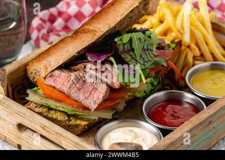 Gegrilltes Steak-Sandwich mit Pommes frites auf einem weißen Porzellanteller Stockfoto