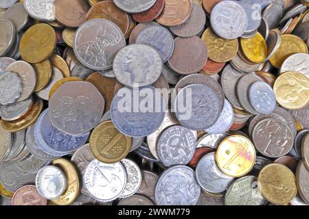 Stapel alter europäischer Münzen vor dem Euro-Währungszeitalter sowie internationaler Münzen. Stockfoto