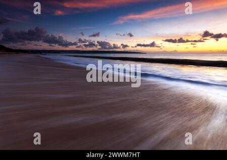 Sonnenuntergang und Wellen am Jimbaran Beach auf Bali Stockfoto