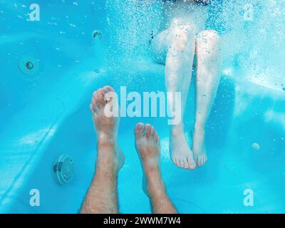 Paar im Whirlpool, Unterwasseraufnahme männlicher und weiblicher Beine im Wasser, selektiver Fokus Stockfoto