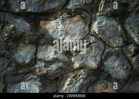 Eine alte Steinmauer steht als zeitloses Denkmal, verwittert und moosbedeckt und zeigt die dauerhafte Schönheit der historischen Architektur. Stockfoto