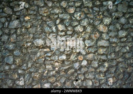 Eine alte Steinmauer steht als zeitloses Denkmal, verwittert und moosbedeckt und zeigt die dauerhafte Schönheit der historischen Architektur. Stockfoto