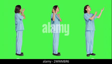 Asiatische medizinische Assistentin erstellt Werbung für neue medizinische Werbekampagne vor Greenscreen Hintergrund. Junge Krankenschwester in Uniform präsentiert links oder rechts mit neuem Werbeslogan. Stockfoto