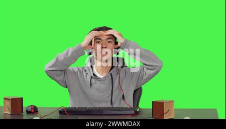 POV des Gamers spielt pc-Spiele am Arbeitsplatz und sitzt auf dem Stuhl über grünem Hintergrund. Online-Player, der Spaß mit Leuten beim rpg-Gaming-Wettbewerb hat und ein Headset an seinem Schreibtisch trägt. Stockfoto