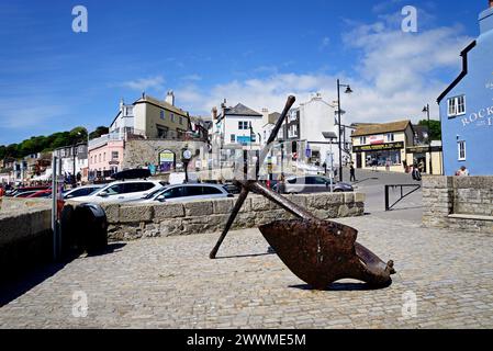 Großer Anker entlang der Küste mit alten Geschäften hinten, Lyme Regis, Dorset, Großbritannien, Europa. Stockfoto