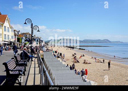 LYME REGIS, Großbritannien - 14. MAI 2022 - Touristen, die sich am Strand und an der Promenade mit Blick auf die Küste entspannen, Lyme Regis, Dorset, Großbritannien, Europa, 14., 2. Mai Stockfoto