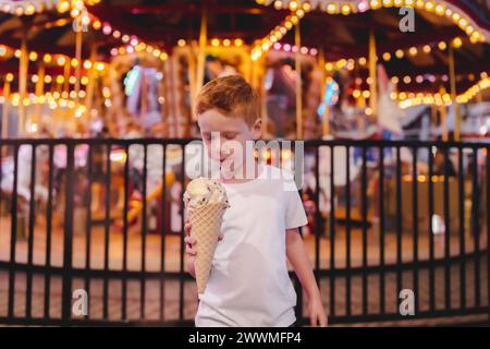 Junger lächelnder Junge, der eine Eiskegel mit Riesenrad hält Stockfoto