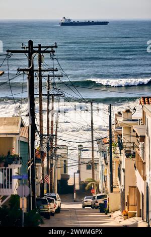 Stromleitungen über Häusern in der Gasse mit Meer im Hintergrund Stockfoto