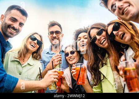 Lachende Gruppe von Freunden, die mit Cocktails tosten - Freundschaft feiern, Sommerfreude feiern, unbeschwerten Outdoor-Spaß - junge Erwachsene mit Getränken in Kunststoff-gla Stockfoto