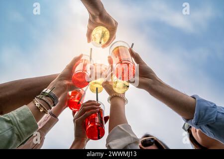Gruppe von Freunden, die mit bunten Drinks toast - Sommerfeier, fröhliche Momente, Partystimmung im Freien - glückliche junge Erwachsene, die Getränke am Himmel holen Stockfoto