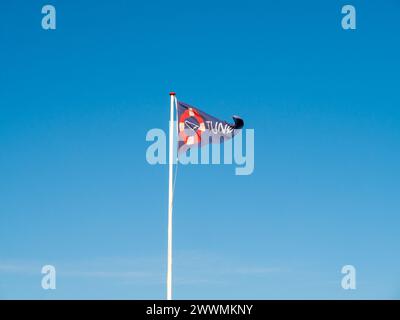 Flatternde dreieckige Flagge mit Schild und Name der Insel Tunø vor einem blauen Himmel, Midtjylland, Dänemark Stockfoto