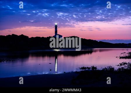 Leuchtturm von Favàritx, bei Nacht, mit den ersten Lichtern des Tages und der Reflexion in der temporären Lagune es Cos des Síndic (Menorca, Balearen) Stockfoto