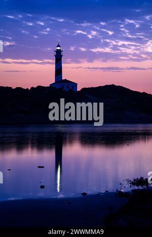 Leuchtturm von Favàritx, bei Nacht, mit den ersten Lichtern des Tages und der Reflexion in der temporären Lagune es Cos des Síndic (Menorca, Balearen) Stockfoto