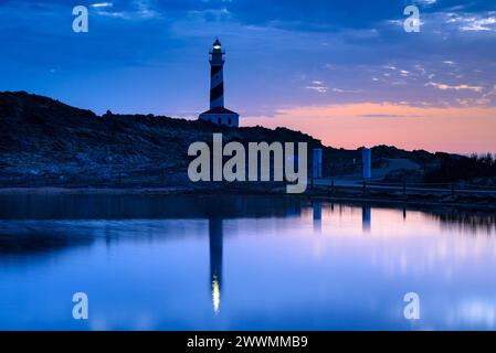 Leuchtturm von Favàritx, bei Nacht, mit den ersten Lichtern des Tages und der Reflexion in der temporären Lagune es Cos des Síndic (Menorca, Balearen) Stockfoto