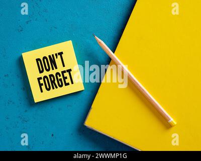 Die Erinnerung nicht vergessen auf gelbem Haftnotizpapier mit Bleistift und Mappe. Stockfoto