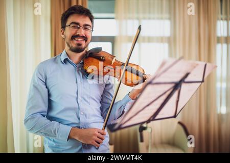 Mann, der zu Hause Geige spielt. Er übt für Live-Auftritte. Stockfoto