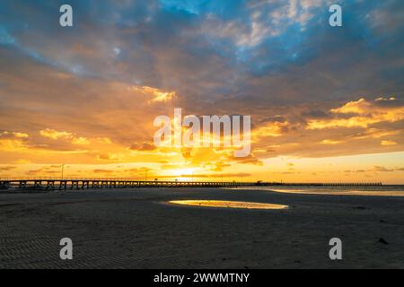 Moonta Bay Beach mit Menschen, die am Steg vor dramatischem Sonnenuntergang spazieren gehen, South Australia Stockfoto