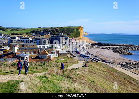 WEST BAY, Großbritannien - 10. OKTOBER 2022 - erhöhter Blick über die Dächer der Stadt in Richtung Strand, Klippen und Landschaft, West Bay, Dorset, Großbritannien. Stockfoto