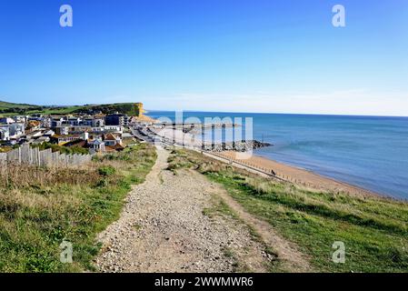 Erhöhte Aussicht über die Dächer der Stadt in Richtung Strand, Klippen und Landschaft vom South West Coast Path, West Bay, Dorset, Großbritannien. Stockfoto