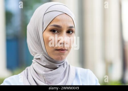 Elegante und bescheidene Frau mit einem neutralen Hijab, der in einer natürlichen Umgebung im Freien aufgenommen wurde. Stockfoto