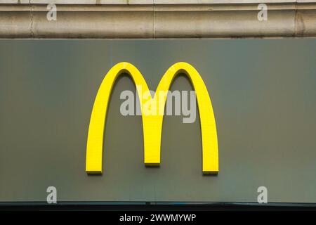 Golden Arches, das urheberrechtlich geschützte Logo für die internationale Fast-Food-Kette McDonalds Burger Outlet. An einer Wand über einer Steckdose in Glasgow montiert, Stockfoto