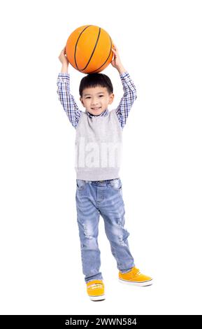 Glücklicher asiatischer Junge, der einen Basketball hält und auf weißem Hintergrund lächelt Stockfoto