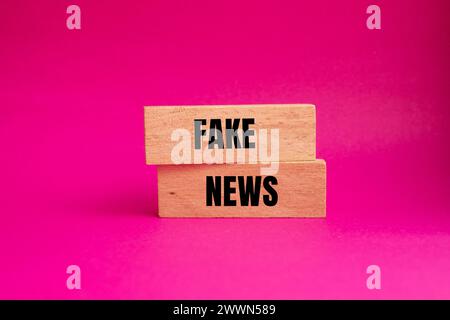 Falsche Nachrichten auf Holzblöcken mit rosa Hintergrund. Konzeptsymbol. Kopierbereich. Stockfoto
