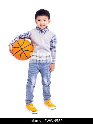 Glücklicher asiatischer Junge, der einen Basketball hält und auf weißem Hintergrund lächelt Stockfoto