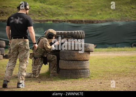 Ein Soldat der albanischen Spezialeinsatzkräfte deckt sich hinter Reifen und feuert sein Gewehr ab, während ein US-amerikanischer Green Beret während eines gemeinsamen Austauschtrainings in der Nähe von Tirana, Albanien, am 27. Februar 2024 zusieht. Albanische Spezialeinsatzkräfte und die 10. SFG(A) führten JCET durch, um die Interoperabilität zu verbessern und die militärische Bereitschaft, die Teamarbeit und das gemeinsame Vertrauen zu stärken und gleichzeitig Frieden und Stabilität in Europa zu fördern. Armee Stockfoto