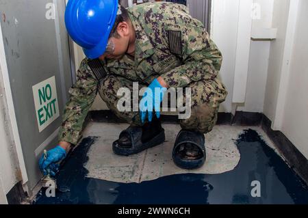 240228-N-RQ159-1074 YOKOSUKA, Japan (28. Februar 2024) Aviation Boatswain’s Mate (Launch and Recovery Equipment) Airman Christian Lazaro, aus Chicago, verteilt Bodenharz mit einem Pinsel in einem Durchgang auf dem einzigen vorwärtsgerichteten Flugzeugträger der US Navy, USS Ronald Reagan (CVN 76), während im Hafen Commander, Fleet Activities Yokosuka, 28. Februar. Ronald Reagan, das Flaggschiff der Carrier Strike Group 5, stellt eine kampfbereite Truppe zur Verfügung, die die Vereinigten Staaten schützt und verteidigt und Allianzen, Partnerschaften und kollektive maritime Interessen in der indopazifischen Region unterstützt. Marineblau Stockfoto