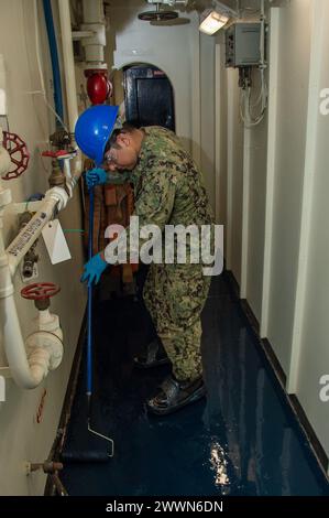 240228-N-RQ159-1057 YOKOSUKA, Japan (28. Februar 2024) Aviation Boatswain’s Mate (Launch and Recovery Equipment) Airman Christian Lazaro, aus Chicago, legt Bodenharz mit einer Walze in einem Durchgang an Bord des einzigen vorwärtsgerichteten Flugzeugträgers der US Navy, USS Ronald Reagan (CVN 76), während im Hafen Commander, Fleet Activities Yokosuka, 28. Februar. Ronald Reagan, das Flaggschiff der Carrier Strike Group 5, stellt eine Kampfgruppe der Vereinigten Staaten zur Verfügung und unterstützt Allianzen, Partnerschaften und kollektive maritime Interessen in der indopazifischen Region. Marineblau Stockfoto