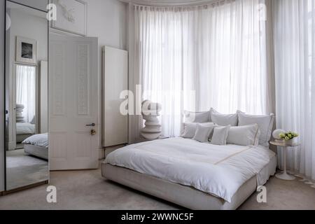 Weißes Schlafzimmer mit moderner Kunstskulptur in West London Apartment, Großbritannien Stockfoto