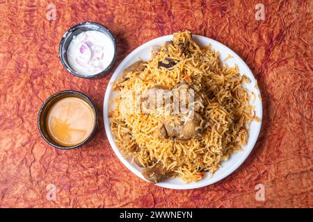 Das berühmte indische Hammel-Biryani-Gericht auf weißem Teller ist köstlich und duftet nach Raita und Soße. Draufsicht Stockfoto