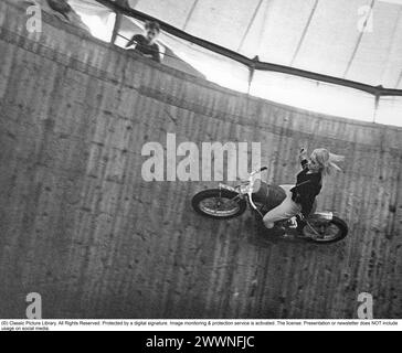 Mauer des Todes 1967. Die Mauer des Todes, das Motordrome, das Velodrome oder der Brunnen des Todes ist eine Nebenausstellung des Karnevals mit einem silos- oder tonnenförmigen Holzzylinder mit einem Durchmesser von normalerweise 6,1 bis 11,0 m (20 bis 36 Fuß) und aus Holzdielen, in der Motorradfahrer entlang der vertikalen Wand fahren und Stunts durchführen. durch Reibung und Zentrifugalkraft gehalten. Die ursprüngliche Mauer des Todes befand sich 1911 auf Coney Island in den Vereinigten Staaten. Ich habe mir einen Motorradfahrer in hoher Geschwindigkeit im Velodrome vorgestellt, der mit den Händen in der Luft zeigte, nicht wie er sollte am Lenker. Bild Elisabeth Stockfoto