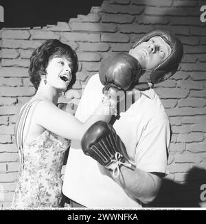 Schauspielerin Lill-Babs Svensson während der Dreharbeiten zum schwedischen Spielfilm Svenska Floyd, in dem Lill-Babs die Sängerin und Schönheit Lollo Fillipini und Carl-Gustaf Lindstedt als Boxer Flosse, alias Svenska Floyd aus Nockeby, spielt. Auf dem Bild sieht man, wie sie einen Aufwärtstrumpf auf seinem Kinn landet. 1961 Kristoffersson Ref. CS14-8 Stockfoto