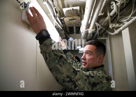 240209-N-VR794-1063 SAN DIEGO (09. Februar 2024) – Information Systems Technician 1st Class Madison Vanzwol aus Vancouver, Washington, ersetzt eine Glühbirne an Bord des amphibischen Angriffsträgers USS Tripoli (LHA 7), Februar 09. Tripoli ist ein amphibisches Angriffsschiff der amerikanischen Klasse, das in San Diego stationiert ist. Marineblau Stockfoto